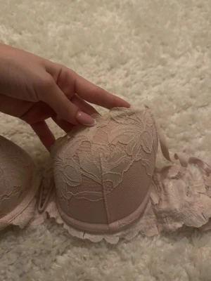 Ljusrosa spets-bh från H&M - Säljer en ljusrosa bh från H&M med vacker spets och blommigt mönster. Bh:n har vadderade kupor och justerbara axelband för bästa passform. Perfekt för dig som gillar romantiska detaljer och mjuka färger. Löser paketpris vid köp av flera bh:ar.