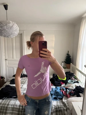 Lila Nike Dri-Fit t-shirt - Säljer en lila Nike Dri-Fit t-shirt med korta ärmar och vit grafisk print framtill. T-shirten har en tight passform och är gjord i ett funktionsmaterial som andas. Perfekt för dig som gillar sportig stil och vill sticka ut med färg.