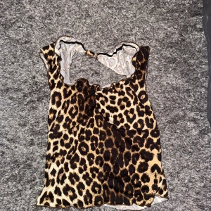 Leopardmönstrad ärmlös topp - Säljer en cool leopardmönstrad topp med ärmlös design och snyggt skuren halsringning, samt öppen i ryggen. Använd endast 2 gånger!