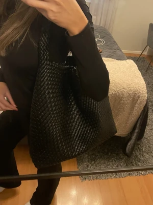 Stor svart axelväska i flätat skinn - Säljer en stor och rymlig svart axelväska med snygg flätad design. 