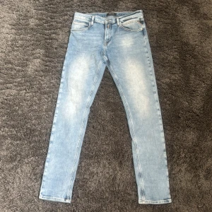 Ljusblå slim jeans från Replay - Säljer ett par ljusblå slim jeans från Replay med klassisk design och snygga slitningar framtill. Jeansen har normal midja, smal passform och är tillverkade i mjukt denimtyg. Perfekta för dig som gillar en clean och stilren look. Jeansen har ca storleken W30 L32