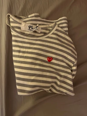 Randig långärmad tröja Comme des Garçons - Säljer en randig långärmad tröja från Comme des Garçons Play i vitt och grått.  Den e storlek s men känns som xs jag e 180 och den e för liten för mig så fråga gärna för fler bilder men om ni e runt 170 borde de ibye vara några problem 
