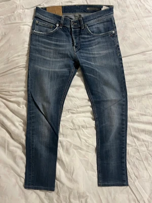 Dondup mius slim fit. - Ett par lite schysstare Dondup mius slim fit i klassisk blå tvätt med snygga slitningar och kontrastsömmar. Modellen har fem fickor, normal passform och raka ben. Materialet är slitstark jeansbomull och bakfickorna. Perfekt för dig som gillar stilrena jeans.