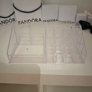 Transparent sminkförvaring i akryl - Snygg och praktisk sminkförvaring i transparent akryl med flera fack i olika storlekar. Perfekt för att organisera sminkborstar, läppstift, läppglans och ögonbrynspennor på sminkbordet. Modern design som passar in i de flesta rum.