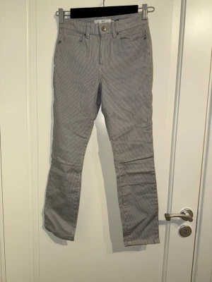 Randiga byxor - Raka randiga byxor med korta ben. Det är blå ränder på en vit bakgrund.