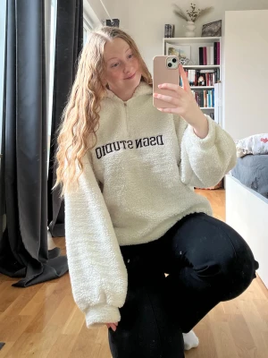 Fluffig hoodie - Vit fluffig hoodie med text ”DSGN STUDIO”. Från Bohoo i storlek M