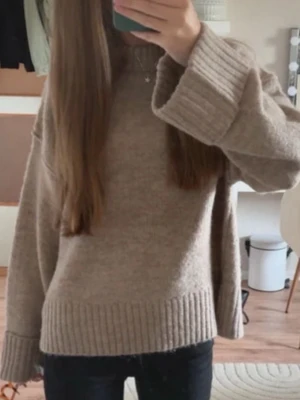 Beige stickad tröja med breda muddar - Säljer en beige stickad tröja från Gina Tricot med breda ribbade muddar vid ärmslut och nederkant. Tröjan har en loose passform, rund hals och långa ärmar. Perfekt för lager-på-lager och chill dagar.