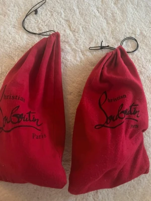 Svarta pumps från Christian Louboutin - Säljer ett par ikoniska svarta pumps från Christian Louboutin med klassisk röd sula. Skorna har spetsig tå, hög klack och är tillverkade i skinn. Kommer med originalröda dustbags. Perfekta för dig som vill ha en lyxig och tidlös look. Strl 29 men passar 38 