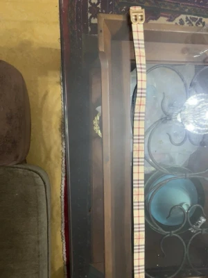 Burberry bälte - Säljer ett snyggt burberry bälte med klassiskt rutigt mönster i beige, rött och svart. Bältet har ett stilrent spänne i metall och är tillverkat i skinn. Perfekt accessoar för att lyfta din outfit.