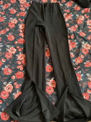 Svarta bootcut-byxor från H&M XS - Snygga svarta bootcut-byxor från H&M i storlek XS. Byxorna har hög midja och vida ben med slitsdetaljer längst ner. Sparsamt använda. 