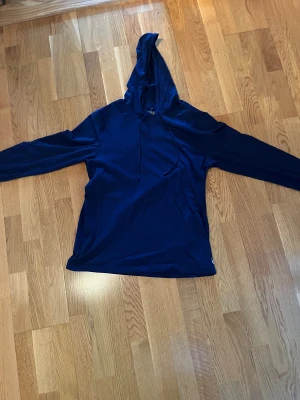 Marinblå hoodie från Polo Ralph Lauren - Snygg marinblå hoodie från Polo Ralph Lauren med klassisk huva och snörning. Tröjan har långa ärmar och är gjord i mjuk bomull. Diskret Polo-logga i vitt nedtill på framsidan. Perfekt för chill dagar och enkel att matcha med jeans eller joggers.