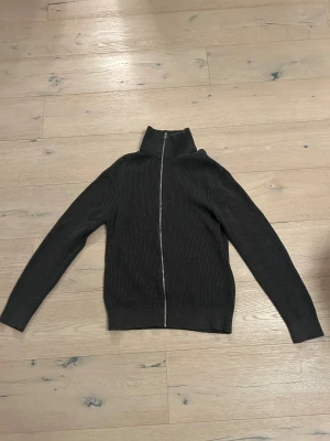 Mörkgrå stickad kofta med dragkedja - Mörkgrå stickad kofta med dragkedja. Enbart använd några få gånger. Passar perfekt nu till vintern för att hålla värmen. 
