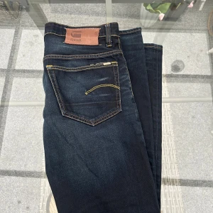 G-Star RAW 3301 herrjeans W33 L32 – mörk denim, slim känsla - Säljer G-Star RAW 3301 herrjeans i storlek W33 L32. Mörk denim med slim känsla och klassiska G-Star-detaljer som kontrastsömmar och ikoniska bakfickor. Bekvämt bomullstyg med lite stretch som ger en snygg passform och premiumkänsla. Fint skick och perfekt för dig som gillar stilrena kvalitetsjeans. 