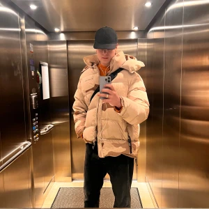 Axel Arigato ” the Nunatak puffer jacket” - Säljer en  pufferjacka från Axel Arigato i beige och brunt camomönster. Jackan har stor huva, dragkedja framtill och två rejäla fickor. Nypris cirka 6000 kr.