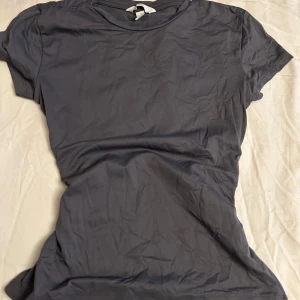 Mörkgrå basic t-shirt - En enkel och stilren mörkgrå t-shirt med rund hals och korta ärmar. Perfekt för dig som gillar en clean look och vill ha ett plagg som funkar till allt. Materialet känns mjukt och skönt mot huden, och passformen är normal.