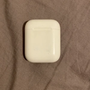 Apple AirPods 2 - Säljer ett par Apple AirPods 2 med laddningsetui. Fungerar utmärkt, synligt normalt slitage på etuiet med några små repor och märken. Hörlurarna är rena och i gott skick. Perfekt för trådlös musik och samtal med enkel anslutning till iPhone. Sitter bara och skräpar hemma mycket skit på den men använda typ 2-4 gånger