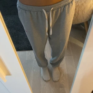 Grå mjukisbyxor med snörning - Säljer ett par grå mjukisbyxor från Ronald McDonald med vit snörning i midjan och ribbade muddar vid bensluten. Byxorna har en relaxed passform och är gjorda i mjukt bomullsmaterial, perfekt för chill dagar hemma. Pris går att diskutera❤️❤️