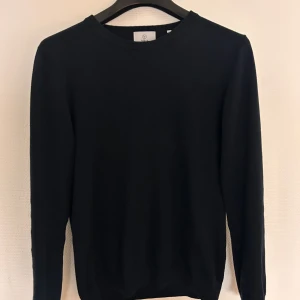 Marinblå stickad tröja från Bläck - En stilren marinblå stickad tröja från Bläck i storlek S. Tröjan har rund hals och långa ärmar, perfekt för dig som gillar enkel och clean look. Materialet är mjukt och skönt, passar bra till jeans eller chinos. Snygg att ha både till skolan och häng med kompisar.