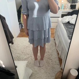 Ljusblå volangklänning  - Supersöt ljusblå klänning med tre lager volanger och v-ringad hals. Klänningen har puffiga halvlånga ärmar och är tillverkad i ett lätt, skrynkligt material som ger en chill vibe. Perfekt till sommarens alla tillfällen!!💕✨