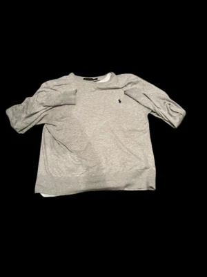 Grå långärmad tröja från Polo Ralph Lauren - Snygg grå långärmad tröja från Polo Ralph Lauren med klassisk rund hals och liten broderad logga på bröstet. Perfekt för dig som gillar stilrena och enkla plagg. Mjuk bomullskvalitet som känns skön mot huden.