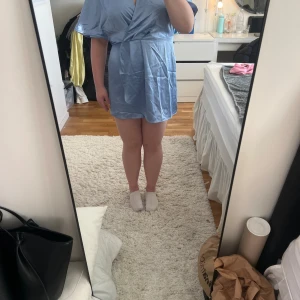 Ljusblå omlottklänning  - Säljer en ljusblå kort omlottklänning från H&M. Klänningen har v-ringning, vida korta ärmar och en markerad midja med dragkedja i sidan. Perfekt för dig som gillar en stilren och fräsch look. Säljer då den inte kommer till användning!!✨💕🩷