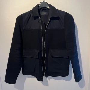 Blå ull jacka från A Day's March - Blå ull jacka med krage och två stora fickor framtill. Jackan har en snygg mix av material med ull, polyester och bomull. Perfekt för lager-på-lager.