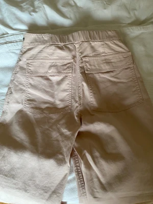 Beige cargo byxor från & Other Stories - Snygga beige/ljus rosa byxor från & Other Stories i storlek 36. De har hög midja, stora fickor både fram och bak samt knapp- och dragkedjestängning. Materialet är mjuk bomull som känns skönt mot huden. Perfekta för varma dagar och chill stil.