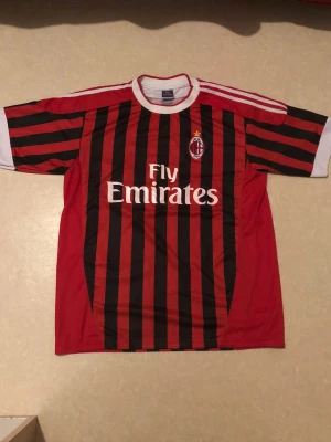 AC Milan El Shaarawy fotbollströja - Säljer en klassisk AC Milan fotbollströja storlek Xl Funkar som L också med El Shaarawy och nummer 92 på ryggen. Tröjan är röd och svart med vertikala ränder, vita detaljer på ärmar och krage samt Fly Emirates tryck på bröstet. Tillverkad i lätt polyester, perfekt för allt oavsett vad.