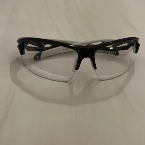 Fat Pipe innebandy glasögon svart/vit - Säljer ett par sportiga Fat Pipe glasögon i svart och vitt med halvbåge och transparenta linser. Snygg, modern design med ventilerade skalmar och Fat Pipe-logga på sidan. Kommer med originalfodral och putsduk. Perfekt för innebandy eller annan träning.