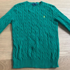 Grön Ralph Lauren tröja!💚💚 - Snygg grön kabelstickad tröja från Ralph Lauren med gul broderad logga på bröstet. Tröjan har rund hals, ribbade muddar och är långärmad. Perfekt för dig som gillar klassisk stil med en färgklick. Tröjan är nästintill oanvänd, inga defekter. 