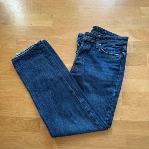 Jack & Jones Loose Chris jeans blå 31/32 - Snygga blå jeans från Jack & Jones i modellen Loose Chris. Jeansen har raka ben och klassisk femficksdesign. Tillverkade i slitstarkt bomullsjeansmaterial med mörkblå tvätt och råa kanter vid benslut.
