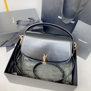 Svart axelväska från Saint Laurent - Säljer en stilren svart axelväska från Saint Laurent i slätt skinn med guldiga metalldetaljer och ikoniska YSL-loggan framtill. Väskan har både handtag och justerbar axelrem, perfekt för att bära på olika sätt. Klassisk och tidlös design som lyfter varje outfit.