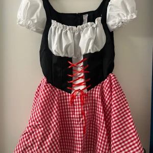 Oktoberfest klänning - Supergullig oktoberfest-klänning. Helt ny, aldrig använd. Vita puffärm och röd snörning framtill. Kjolen är röd- och vitrutig med klassisk folkloristisk vibe. Pris kan diskuteras 🫶🏼