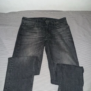 Svarta tapered jeans från Jack & Jones - Säljer ett par svarta jeans från Jack & Jones i modellen Mike Tapered. Jeansen har klassisk femficksdesign, normal midja och avsmalnande ben. Materialet är jeans med en lätt tvättad look som ger en cool vibe. Perfekta för dig som gillar en avslappnad men ändå snygg stil.