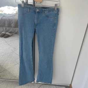 Ljusblå bootcut/flare jeans från H&M - Säljer ett par ljusblå jeans från H&M med bootcut och låg midja. Jeansen har justerbar midja och snyggt utsvängda ben. Jeansen har stretchigt och skönt material. Har använt ett par gånger och har små trådar (bild 5) som knappt syns