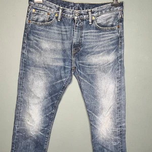 Levi's 508 blå jeans W32 L32 - Säljer ett par Levi's 508 jeans i klassisk blå tvätt med slitningar och snyggt blekta partier. Jeansen har fem fickor, gylf med dragkedja och raka ben. Perfekta för dig som gillar en avslappnad men ändå stilren look.