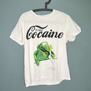 Vit t-shirt med Kermit tryck - Det gör ont i själen att släppa denna goding, har fått utskällningar av lärare, skratt av farbröder men eftersom den nu är för liten ska den vidare.