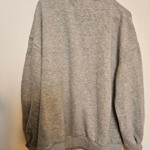 Grå oversized sweatshirt från Bershka - Enkel och stilren grå sweatshirt från Bershka i oversized modell. Tröjan har långa ärmar med breda muddar och en klassisk rund halsringning. Storlek S. 