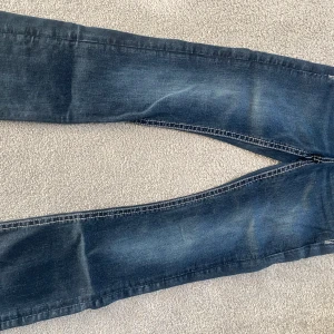 Blå jeans från Gina Tricot stl 152 - Snygga blå jeans från Gina Tricot med kontrastsömmar och dekorativ knapp framtill. Jeansen har klassisk femficksdesign och coola detaljer på bakfickorna. Perfekt för dig som gillar en avslappnad och trendig look.