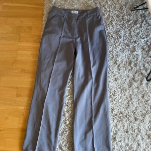 Grå kostymbyxor från Madlady - Snygga grå kostymbyxor från Madlady med raka ben och pressveck.