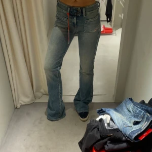 Diesel bootcut jeans  - Snygga ljusblå bootcut jeans från Diesel med klassiska fickor både fram och bak. Jeansen har en cool tvätt och en röd detalj vid gylfen som sticker ut. Perfekta för dig som gillar en retro vibe och vill ha ett par jeans som sitter riktigt bra.