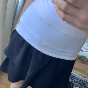 Svart volangkjol med resårmidja - Säljer en svart kortkjol med volang och bred resår i midjan. Kjolen har en flowy känsla och sitter bekvämt på höften. Perfekt för dig som gillar en enkel men snygg stil. Högmidjad men går att vika över💕