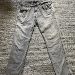Replay grå jeans, storlek 32/30 - Snygga grå jeans från Replay i klassisk femficksmodell. Jeansen har raka ben och diskreta detaljer på bakfickorna. Tillverkade i mjukt denimtyg som ger en skön känsla och passar perfekt till en avslappnad stil.
