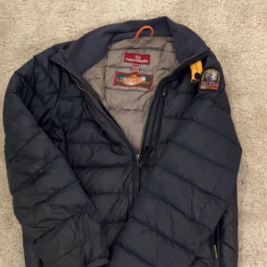 Svarr lättviktsdunjacka Parajumpers - Säljer en svart lättviktsdunjacka från Parajumpers med klassisk patch på ärmen och gul detalj vid kragen. Jackan har dragkedja framtill, två sidofickor med dragkedja och en bröstficka. Perfekt för kyliga dagar och riktigt skön passform., priset där av är för den har en liten skada på armen men har lagat de, men det syns lite