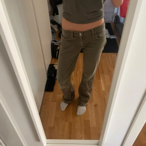 Lågmidjade gröna byxor från 7 For All Mankind - Snygga lågmidjade byxor från 7 For All Mankind i en olivgrön nyans. Byxorna har klassisk femficksdesign, raka ben och är tillverkade i ett mjukt bomullsmaterial med lite stretch. Perfekta för dig som gillar en avslappnad men ändå stilren look.