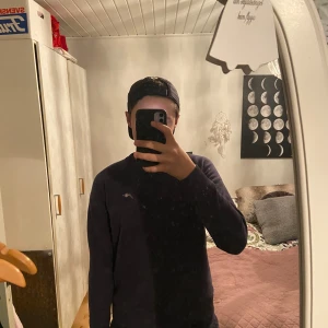 Mörkblå sweatshirt från GANT - Säljer en stilren mörkblå sweatshirt från GANT med liten broderad logga på bröstet. Tröjan har rund halsringning med snygg randig detalj på insidan, långa ärmar och ribbade muddar. Perfekt för dig som gillar klassisk och enkel stil.