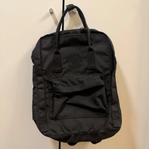Svart Kånken ryggsäck från Fjällräven - Helt nytt oanvänd! Klassisk svart Kånken ryggsäck från Fjällräven med broderad logga framtill. Ryggsäcken har ett stort huvudfack, framficka med dragkedja och två handtag upptill. Tillverkad i slitstark syntet och perfekt för vardagsbruk eller skola.