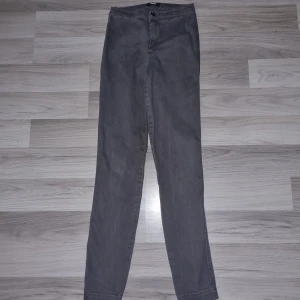 Gråa slim jeans från Bik Bok - Gråa jeans från Bik Bok med smal passform och klassisk design. Byxorna har knapp och dragkedja framtill samt raka ben. Perfekta för dig som gillar en enkel och stilren look. Materialet är mjukt och stretchigt för extra komfort.