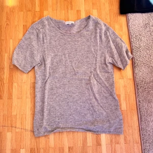 Grå t-shirt i kashmir från Davida - Mjuk och lyxig grå t-shirt från Davida i kashmir. Klassisk rund halsringning och korta ärmar. Perfekt för dig som gillar en enkel men exklusiv stil. Passar till allt och känns superbekväm mot huden.