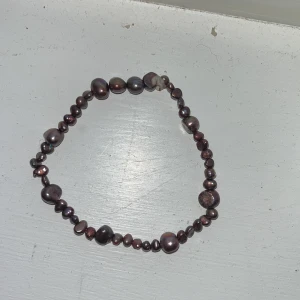 Brunt/lila  pärlarmband med oregelbundna pärlor - Unikt armband med oregelbundna bruna och lila pärlor i olika storlekar och former. Pärlorna har en skimrande yta som ger coola färgskiftningar i ljuset. Perfekt accessoar för dig som gillar personliga smycken med naturlig känsla.